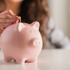 person dropping money into a piggy bank